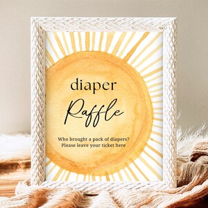 Könnte beinhalten: Ein weißer Rahmen mit einer gelben Sonnengrafik und dem Text "diaper raffle" in Schwarz. Der Text darunter lautet "Wer hat eine Packung Windeln mitgebracht? Bitte hinterlassen Sie Ihr Ticket hier."