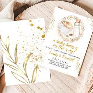 K&ouml;nnte beinhalten: Eine wei&szlig;e Babyparty-Einladung mit goldenen Akzenten. Die Einladung zeigt eine Kaffeetasse und eine Babyflasche mit einem Kranz aus Bl&auml;ttern und Blumen. Der Text lautet "a baby bean is on the way!" und enth&auml;lt die Namen "Emily & Ronald" sowie das Datum und die Uhrzeit der Party.