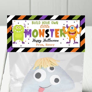 May include: A Halloween treat bag with a label that says "Build your own little monster. Happy Halloween. From, Henry". The label has a green and orange monster on it. The bag is clear and has a blue monster inside.