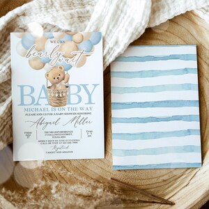 May include: A baby shower invitation with a blue and white striped background. The invitation features a cartoon teddy bear in a hot air balloon with the text "We can barely wait Baby Michael is on the way".