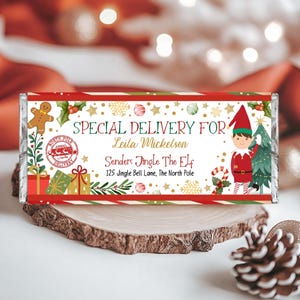 Peut inclure: Un emballage de chocolat de Noël rouge et vert avec un motif festif. L'emballage indique "LIVRAISON SPÉCIALE POUR Leila Mickelson Expéditeur : Jingle The Elf 125 Jingle Bell Lane, Le Pôle Nord".