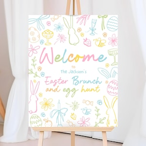 Puede incluir: Un letrero de bienvenida para el brunch de Pascua en colores pastel sobre un caballete. El letrero presenta la palabra "Welcome" en un degradado arcoíris, junto con garabatos con temas de Pascua como conejitos, huevos y flores. También se incluye el texto "Easter Brunch and egg hunt".