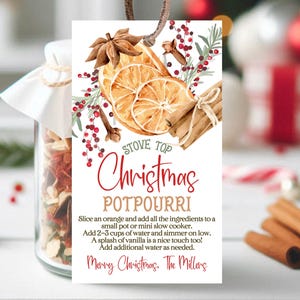 Könnte beinhalten: Ein druckbarer Geschenkanhänger mit einer Aquarell-Illustration eines Weihnachts-Potpourris. Der Anhänger zeigt ein rotes und grünes Blumenmuster mit einer Orangenscheibe, Zimtstangen und Sternanis. Der Text lautet "Stove Top Christmas Potpourri" und enthält Anweisungen zur Herstellung des Potpourris. Der Anhänger ist mit "Frohe Weihnachten, Die Millers." signiert.