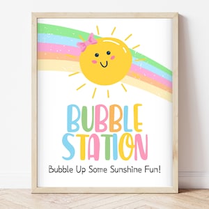 Könnte beinhalten: Ein druckbares Schild mit einer gelben Sonne mit einer rosa Schleife, einem Regenbogen und dem Text "Bubble Station" in bunten Buchstaben. Der Text darunter lautet "Bubble Up Some Sunshine Fun!"