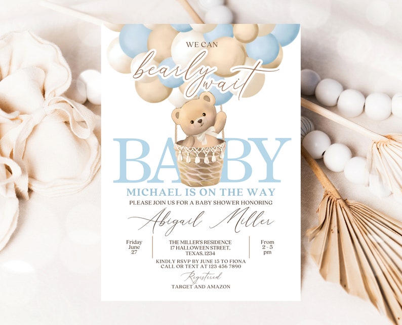 May include: A baby shower invitation with a blue and beige color scheme. The invitation features a teddy bear in a hot air balloon made of balloons. The text on the invitation reads "We can barely wait" and "Baby Michael is on the way".