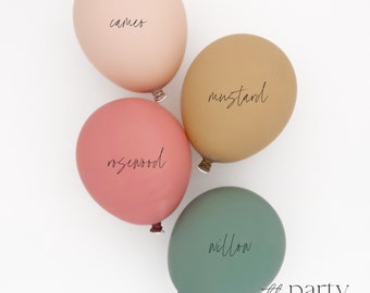 May include: Four balloons in different colors with names written on them: cameo, mustard, rosewood, and willow. The balloons are on a white background.