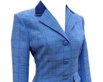May include: A light blue blazer with a white collar and a blue trim. The blazer has a checkered pattern and three buttons. The text "NADS INTERNATIONAL" is printed on the bottom right side of the blazer.