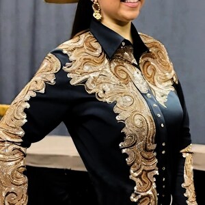 May include: Black long-sleeve shirt with gold embroidery. The embroidery features a swirling, ornate design.