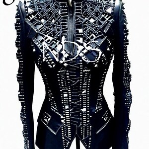 May include: Black leather jacket with a cut-out design and silver studs. The jacket has a zipper closure and long sleeves.