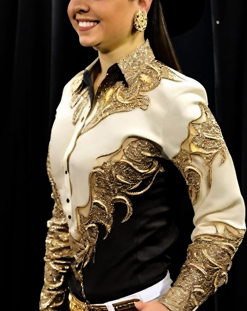 May include: A white and black long-sleeved shirt with gold embroidery. The shirt has a button-up front and a pointed collar.