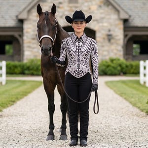 May include: A dark brown horse with a white halter stands next to a person wearing a black cowboy hat, black gloves, black trousers, and a long-sleeved shirt featuring a detailed white and black geometric pattern with a structured, pointed hem.