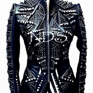 May include: A black leather jacket with a zipper closure and a geometric design. The jacket is covered in silver studs and has a high collar.