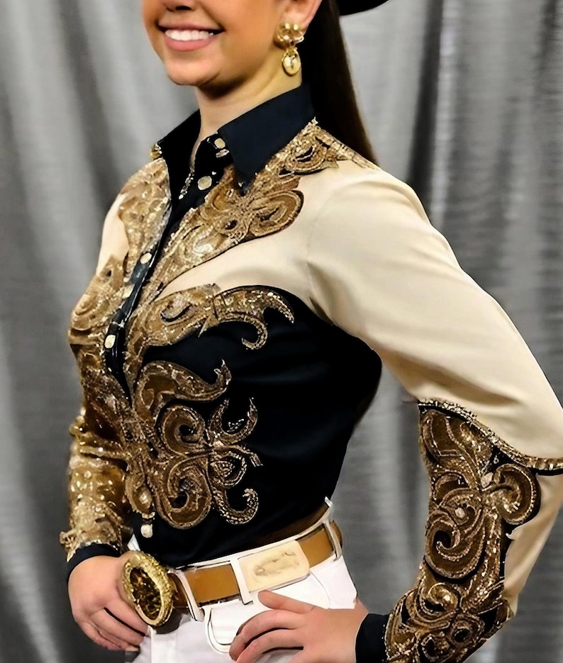 May include: A black and beige long-sleeved shirt with gold embroidery. The shirt has a button-up collar and a brown belt.
