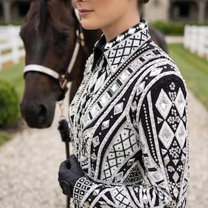 May include: A black long-sleeved show shirt featuring intricate white and silver geometric patterns, embellished with numerous clear crystals, metallic studs, and diamond-shaped accents across the collar, shoulders, and torso.