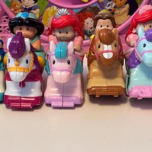 May include: A collection of colorful toy figures, each riding a horse or unicorn. The figures are dressed in various outfits, with blonde, brown, and black hair. The horses and unicorns are in shades of pink, blue, brown, and white.