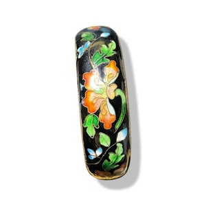 Op de afbeelding: Een zwarte emaille armband met een bloemenontwerp. De bloemen zijn oranje, groen en blauw.