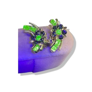 Pode incluir: Um par de brincos vintage de clip com um design floral. Os brincos apresentam strass verdes e pretos.