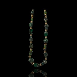 May include: A green and gold necklace with various sized and shaped beads. The necklace is made of glass and metal.