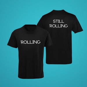 Puede incluir: Camiseta negra con texto blanco que dice "ROLLING" en la parte delantera y "STILL ROLLING" en la parte trasera.