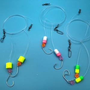 May include: Three fishing rigs with different colored beads and floats. The rigs are made with clear fishing line and have swivels and hooks.