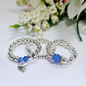 Zilveren stretch stapelringen voor kralen. Set van 3. Inclusief hartbedel. Zilveren en blauwe stenen ringen. Sprankelende blauwe geboortesteenringen