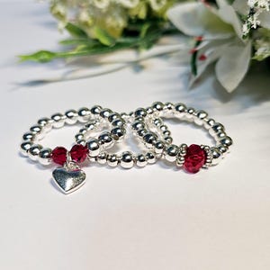 Sparkling Silver bead stretch stacking rings with heart charm & red ruby coloured stones. Silver stretch January July birthstone rings stack