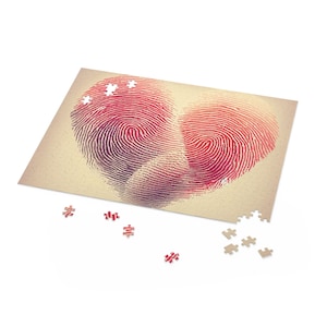 May include: A heart-shaped puzzle with a fingerprint design in shades of red and purple. Several puzzle pieces are scattered around the partially assembled puzzle, which sits on a beige background. The puzzle is a romantic gift.
