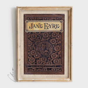 May include: A framed print of the book cover for "Jane Eyre: Household Edition". The cover features a brown leather-like background with a gold embossed title and a floral design. A butterfly is depicted in the center of the design.