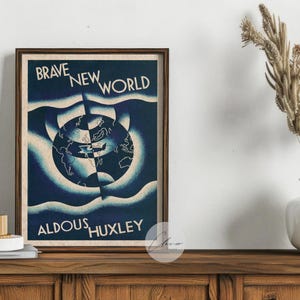 May include: A framed print of Aldous Huxley's "Brave New World" with a blue and white globe design. The print is displayed on a wooden cabinet. A white vase with dried plants and a small white mug are also visible.