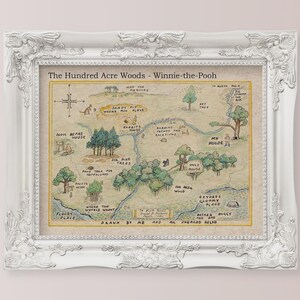 May include: A framed print of a map of the Hundred Acre Woods from Winnie-the-Pooh. The map is hand-drawn with watercolor-style illustrations and text. The white frame has ornate detailing.