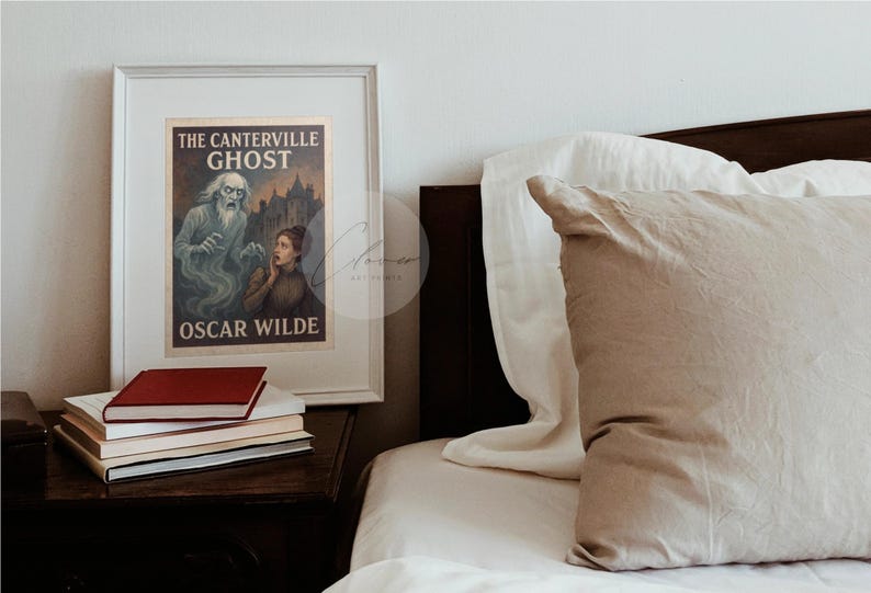 May include: A framed print of "The Canterville Ghost" by Oscar Wilde, with a ghostly figure and a woman in a vintage style. The print is on a nightstand with books, next to a bed with pillows and a white duvet. The frame is white.