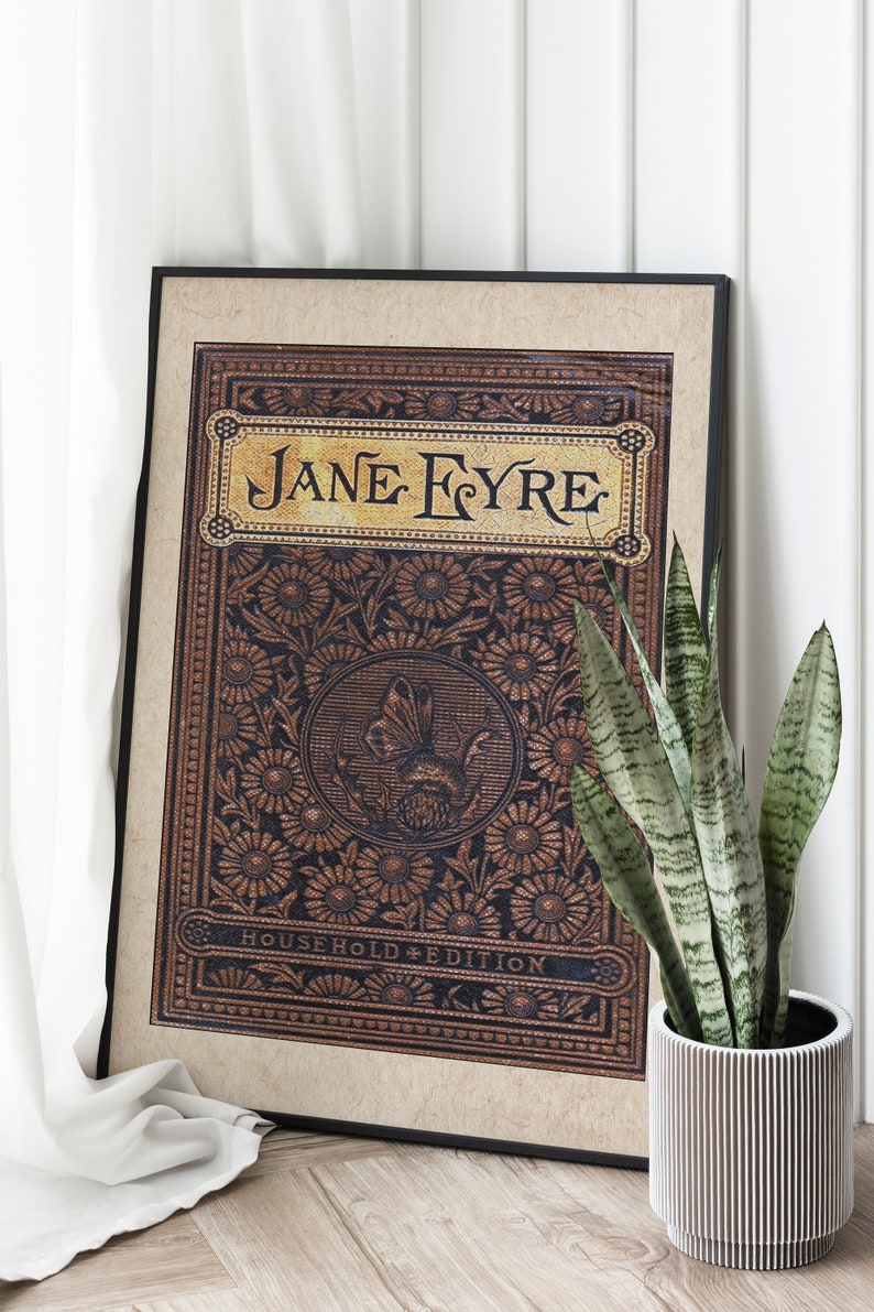 May include: A framed print of the book cover for "Jane Eyre" with a decorative floral design and the text "Household Edition".