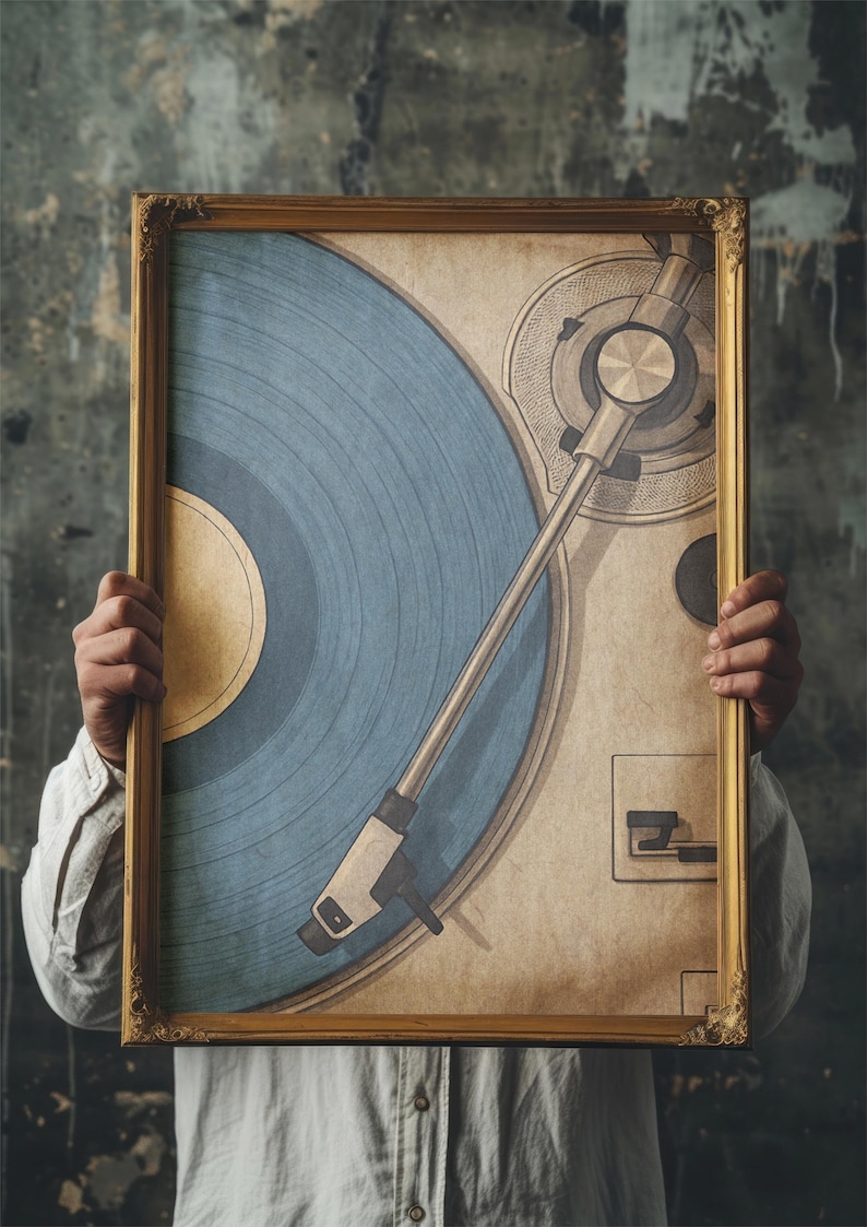 May include: A framed print featuring a vintage-style illustration of a record player. The artwork showcases a blue vinyl record and a beige background, all within a gold-colored ornate frame. The image is held by a person.