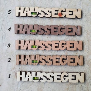 May include: Five wooden plaques with the word "Haus Segen" written on them. Each plaque has a small level attached to it. The plaques are numbered 1 through 5.