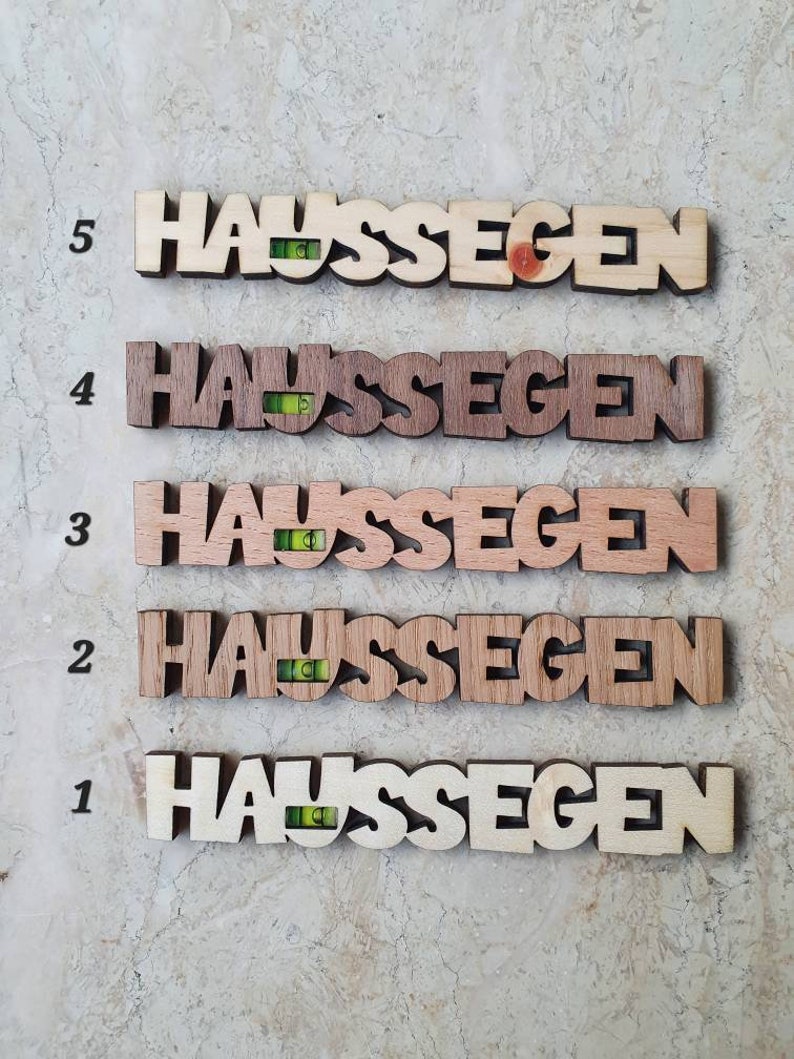 May include: Five wooden plaques with the word "Haus Segen" written on them. Each plaque has a small level attached to it. The plaques are numbered 1 through 5.