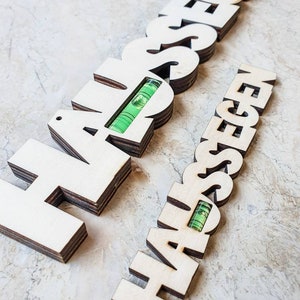 May include: Two wooden signs with the word "HAPPINESS" spelled out in large letters. Each sign has a level built into it, with the bubble centered.