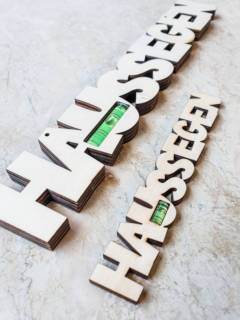 May include: Two wooden signs with the word "HAPPINESS" spelled out in large letters. Each sign has a level built into it, with the bubble centered.