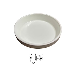 May include: White ceramic saucer, a simple and elegant dish for serving or displaying small items.