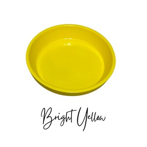 May include: A bright yellow ceramic bowl. The bowl is round and shallow, with a smooth, glossy finish.