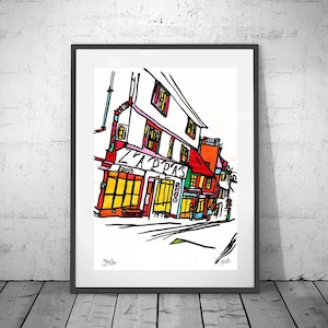 Puede incluir: Una impresión artística enmarcada de una colorida escena callejera. La obra de arte representa un edificio con el texto "ZAPPAS" sobre las ventanas. El edificio está representado en colores brillantes, incluyendo rojo, amarillo y naranja, con contornos negros.