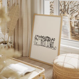 May include: A framed art print featuring a minimalist line drawing of a group of people. The artwork is in black on a cream background, set in a light wood frame. The print is displayed in a bright, airy room with natural light.