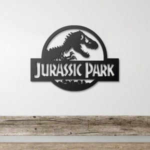 May include: Black metal wall decor featuring the Jurassic Park logo with a dinosaur silhouette and the text "Jurassic Park".