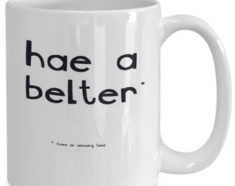 May include: White ceramic mug with black text that reads "hae a belter" and "have an amazing time".