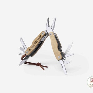 Può includere: Un multi-utensile con manico in legno e un'incisione personalizzata che recita "Nonno Massimo". Lo strumento ha una varietà di accessori, tra cui pinze, un coltello, una sega e un cacciavite.