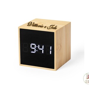 Puede incluir: Un reloj digital de madera con una pantalla negra que muestra la hora 09:41. El reloj tiene una inscripción personalizada en la parte superior que dice "Vittorio e Jole".