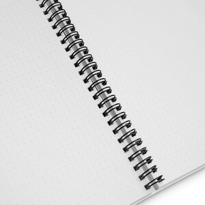 May include: A white notebook with a black wire-o binding. The notebook has a dotted grid pattern on the pages.