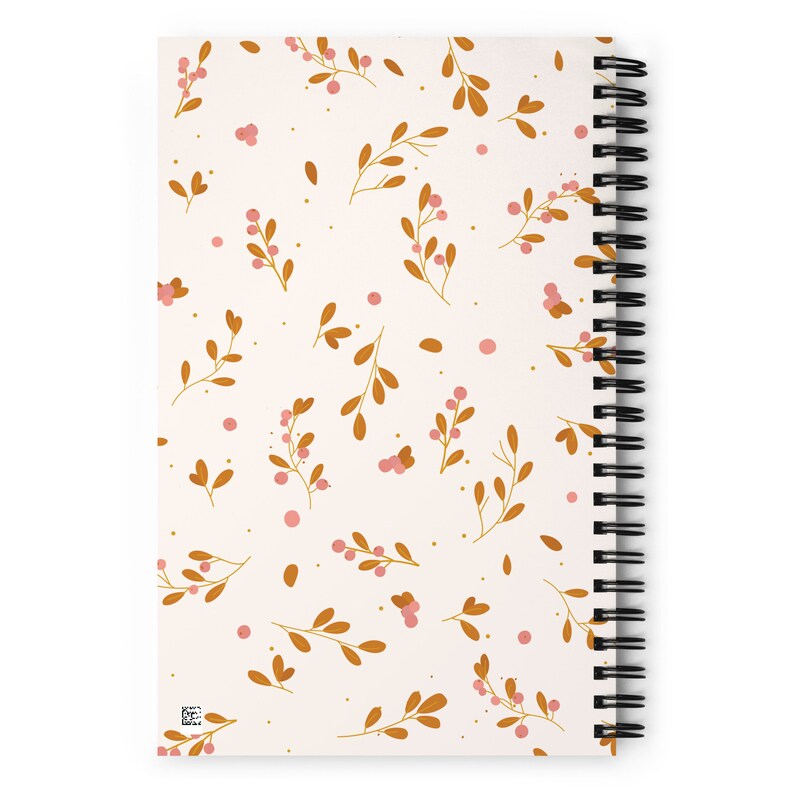 May include: A white spiral notebook with a floral pattern. The pattern features small pink berries and brown branches on a white background.