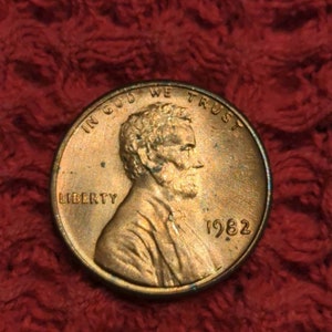 Puede incluir: Un centavo estadounidense de cobre de 1982 con las palabras "In God We Trust" y "Liberty" en el anverso, y el año "1982" en el reverso.