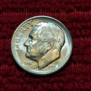 Puede incluir: Una moneda de diez centavos de dólar estadounidense de plata con el año 1955 y la palabra "LIBERTY" inscrita en el lateral. La moneda presenta un perfil de un rostro masculino.