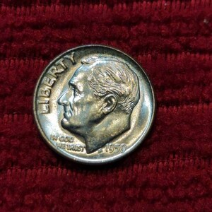 May include: A silver US dime coin with the year 1959 and the words "Liberty" and "In God We Trust" inscribed on it.